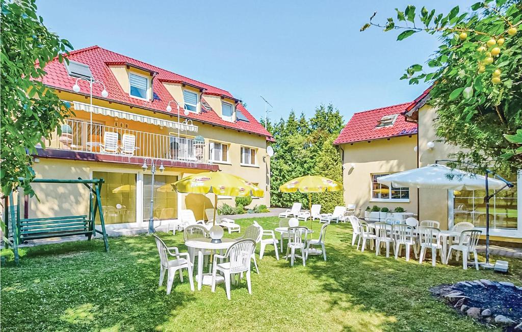 a group of tables and chairs with umbrellas in a yard at Cozy Home In Grzybowo With Ethernet Internet in Grzybowo