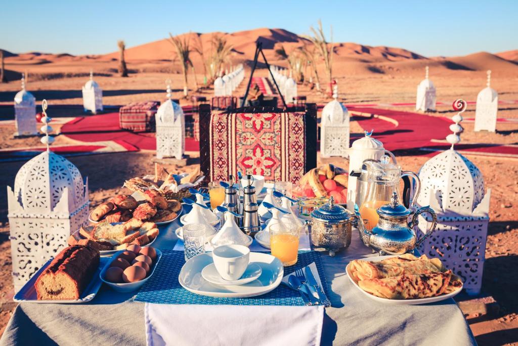 a table with plates of food on it in the desert at Luxury Desert Camp Amanar in Merzouga