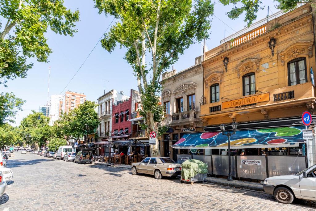 uma rua numa cidade com carros estacionados em frente a edifícios em Granados Hostel em Buenos Aires