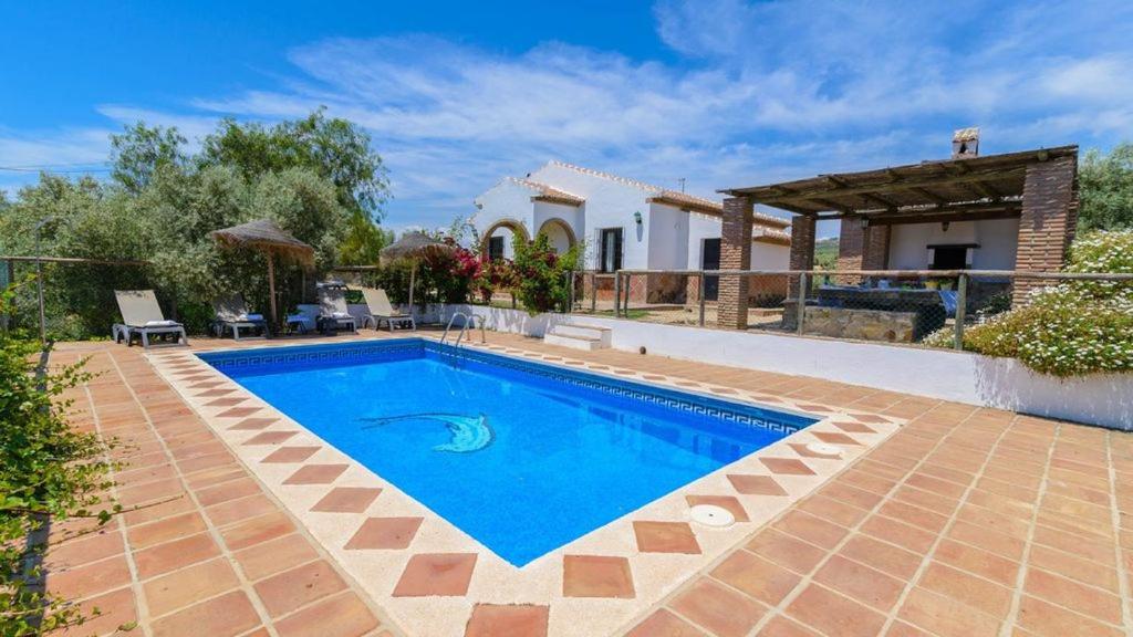 a swimming pool in front of a villa at Casa Rural El Moral in Málaga