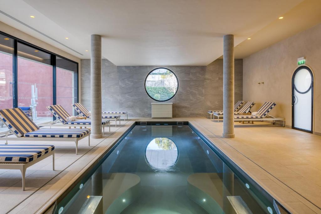 einen Pool in einem Zimmer mit Stühlen und einem Pool in der Unterkunft Maison Albar Hotels L’Imperator in Nîmes