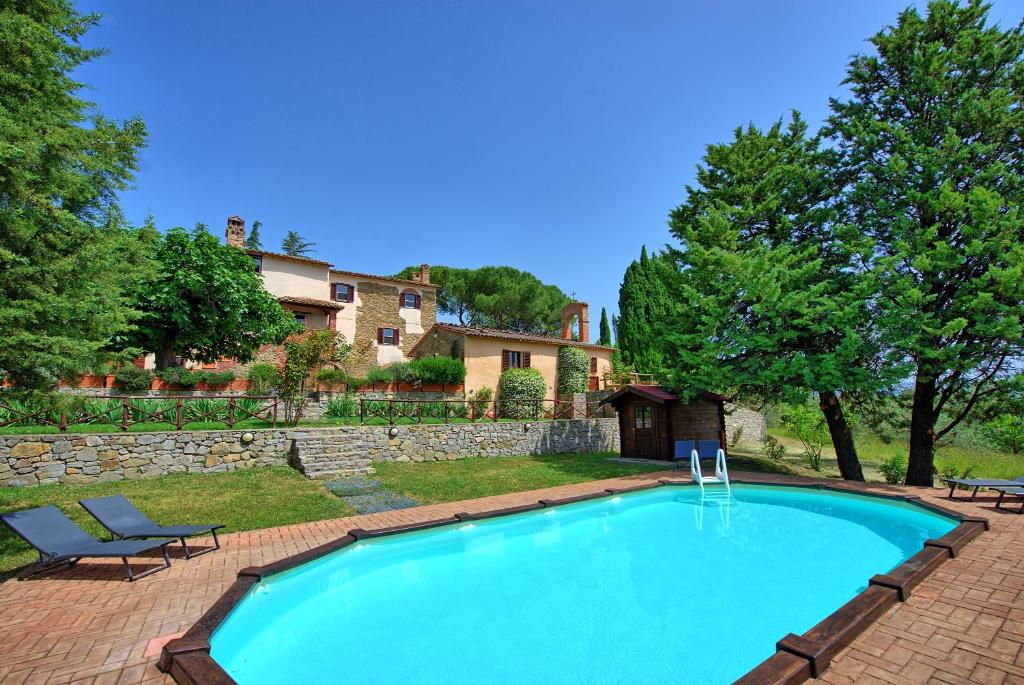 a large swimming pool in a yard with a house at Villa Uccellaia by PosarelliVillas in Agello