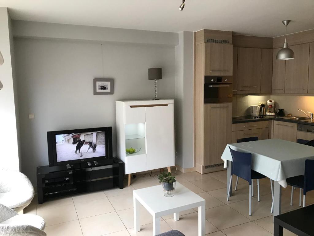 a living room with a table and a tv and a kitchen at Appartement Koksijde in Koksijde