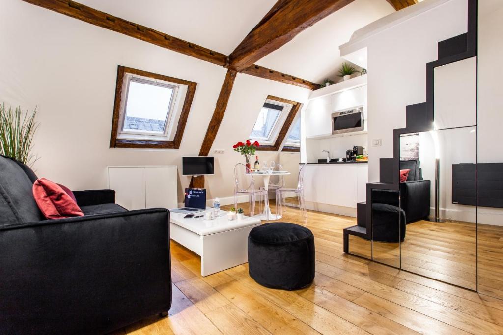 ein Wohnzimmer mit einem schwarzen Sofa und einem Tisch in der Unterkunft CMG Concorde/ Madeleine in Paris