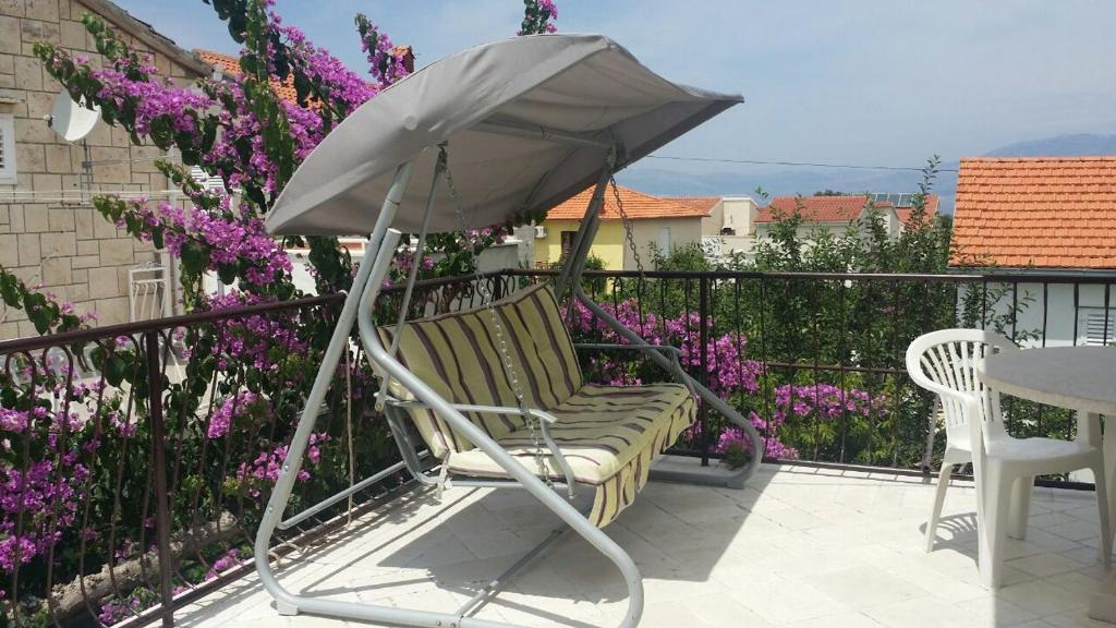 una sedia e un ombrellone su un balcone con fiori viola di Apartment Pehi a Supetar (San Pietro di Brazza)