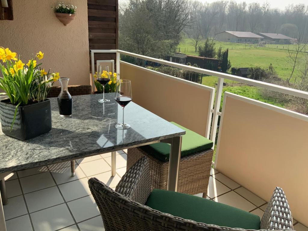 einen Balkon mit einem Tisch und 2 Gläsern Wein in der Unterkunft Annes Ferienwohnung Freiburg in Vörstetten