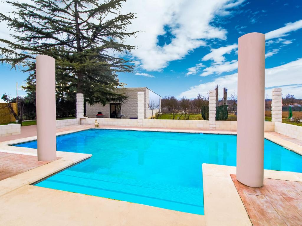 a swimming pool with two white columns in front of a house at Belvilla by OYO La Casa de Valen in Villamuriel de Cerrato