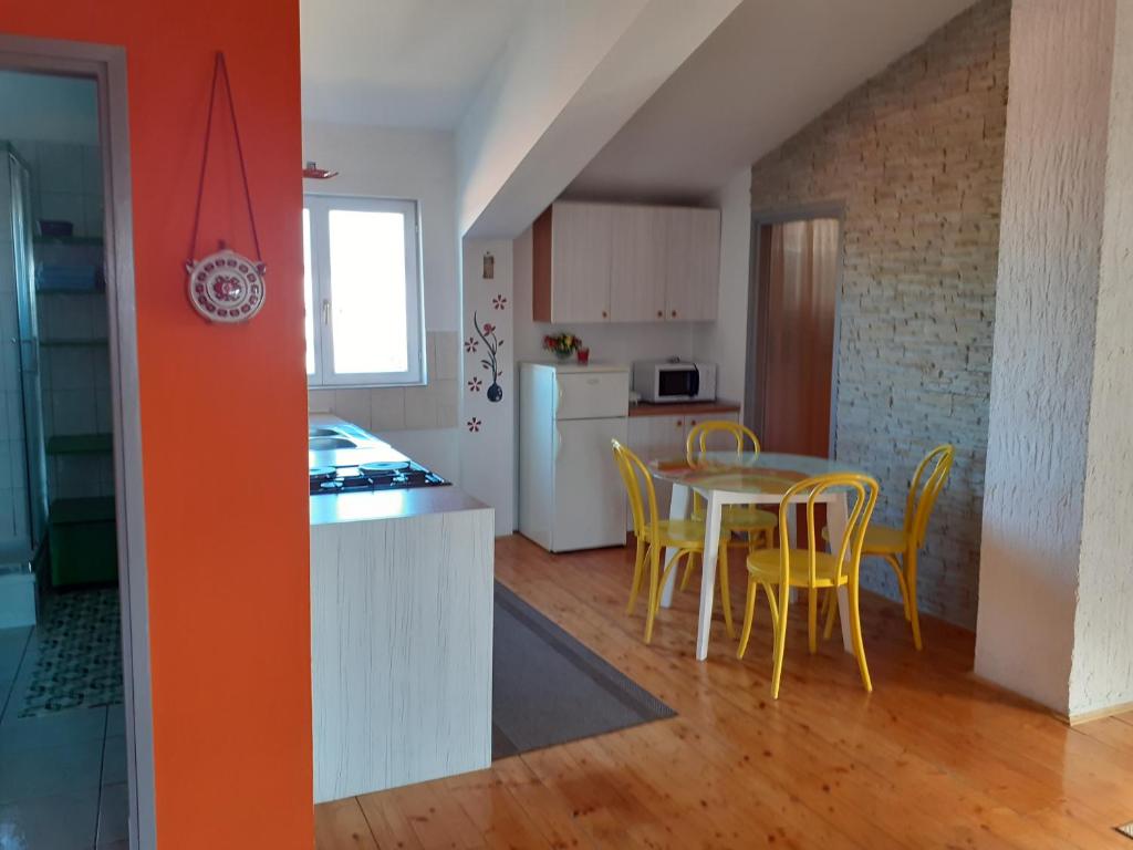 a kitchen and dining room with a table and yellow chairs at Apartments Piero in Zadar