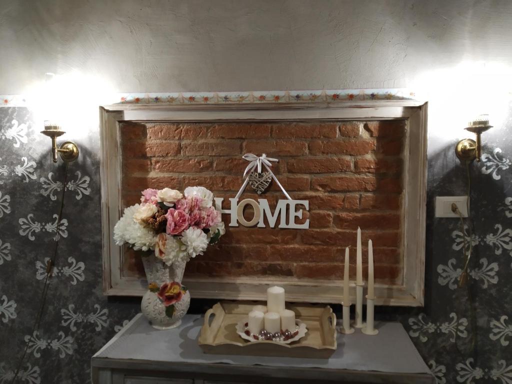 a fireplace with a sign that reads home with flowers and candles at Piccola Casa Shabby 500m castello di Este in Este