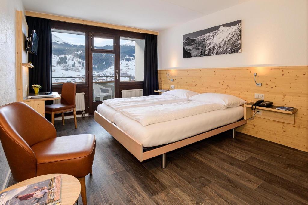 um quarto com uma cama grande e uma cadeira em Jungfrau Lodge, Annex Crystal em Grindelwald