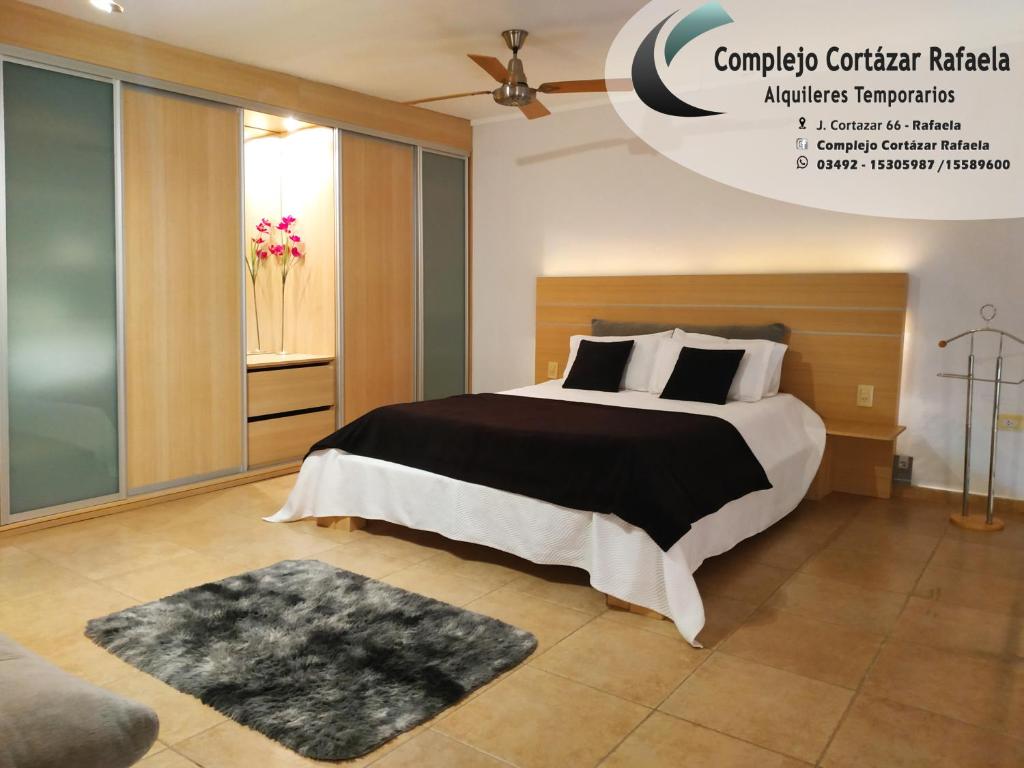 1 dormitorio con 1 cama grande con almohadas blancas y negras en Complejo Cortazar Rafaela en Rafaela