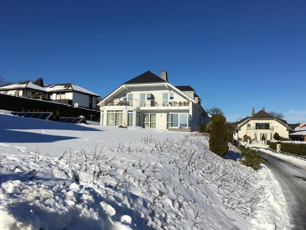 a snow covered yard with a house in the background at Ferienwohnung Hochwaldblick 3 in Morbach