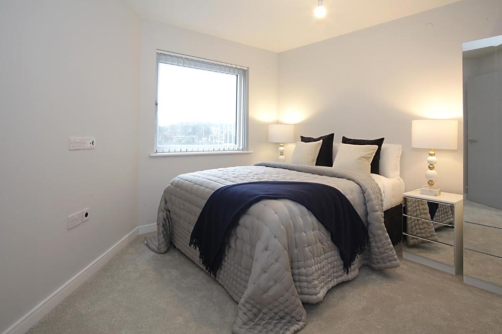 a white bedroom with a large bed with a window at Foundry luxury new one bedroom apartments close to town center in Luton