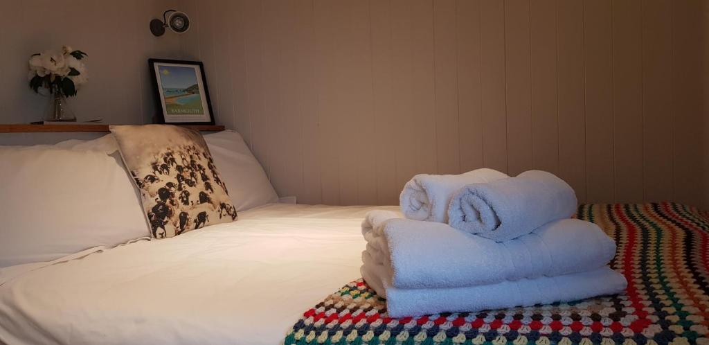 a room with a bed with folded towels on it at The Farm Hut in Barmouth