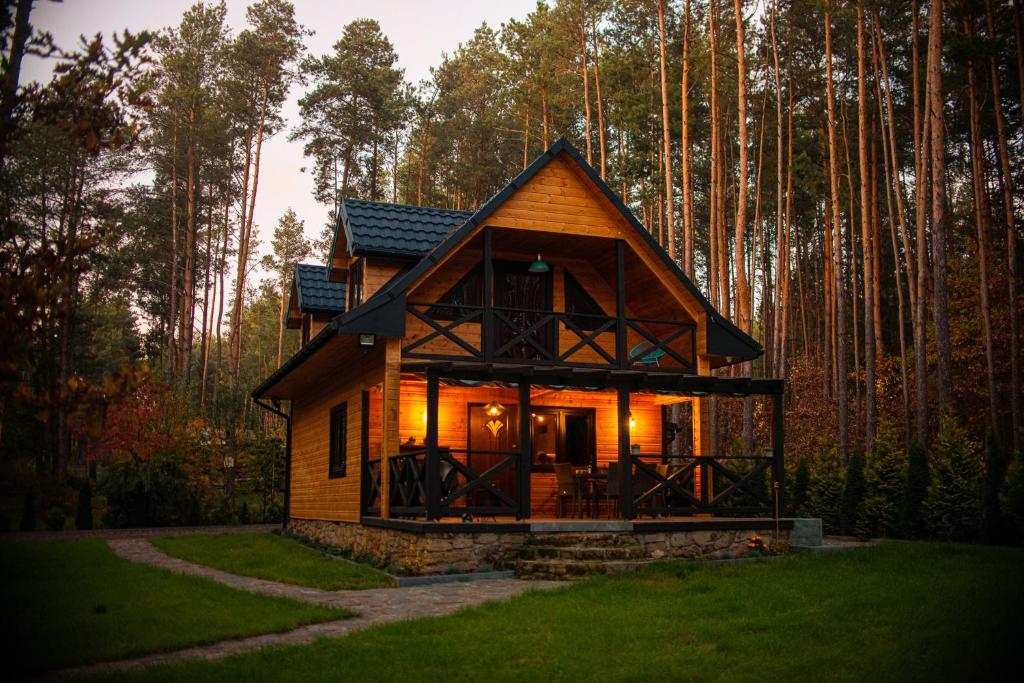 Une petite maison dans les bois avec les lumières allumées dans l'établissement Domek w lesie nad zalewem, à Chańcza