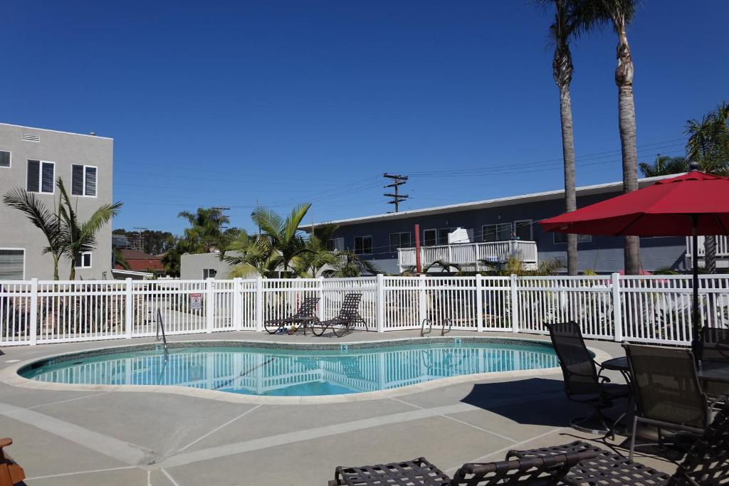 a swimming pool with chairs and a white fence at Seaside Village Carlsbad in Carlsbad