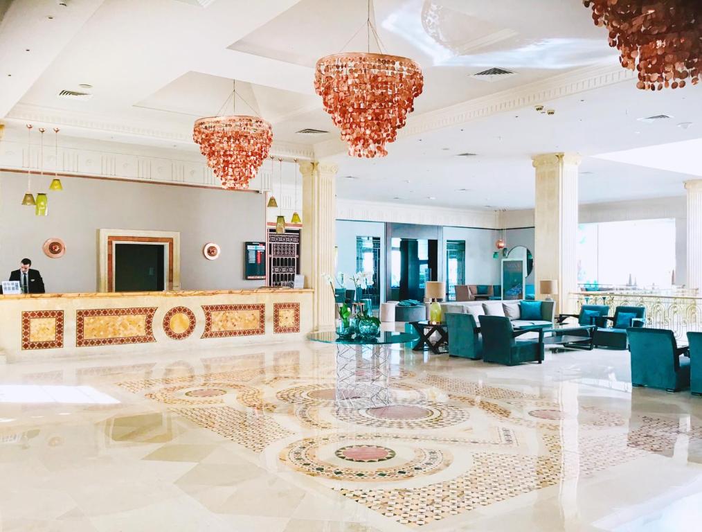 a lobby with blue chairs and chandeliers at Royal Thalassa Monastir in Monastir