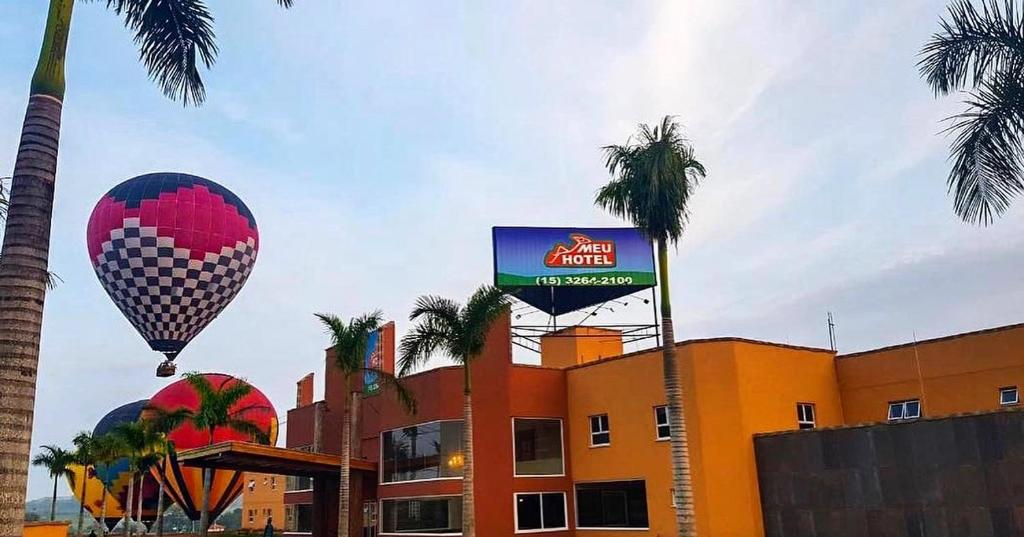 博伊圖瓦的住宿－Meu Hotel Boituva，飞过棕榈树建筑的热气球