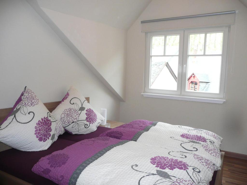 łóżko z fioletowymi i białymi poduszkami i oknem w obiekcie Mosel Ferienhaus Bernkastel w mieście Bernkastel-Kues