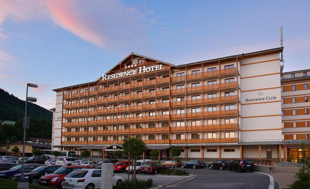 un hotel con un montón de coches aparcados en un estacionamiento en Apartman JATI 319 - Donovaly, en Donovaly