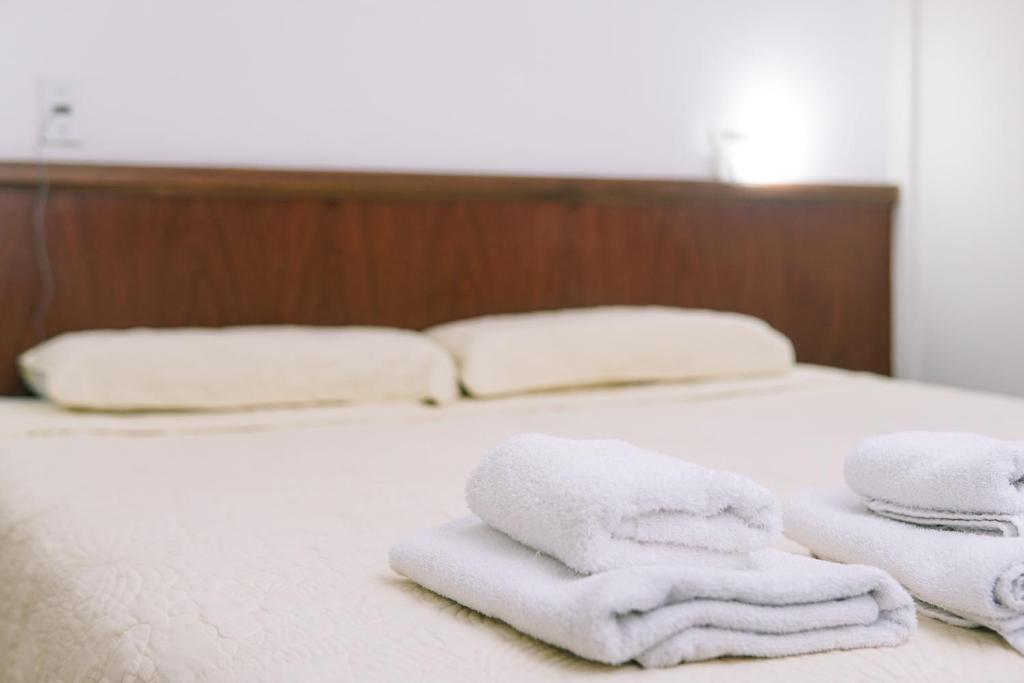 2 weiße Handtücher auf einem Bett liegen bereit. in der Unterkunft Hotel Garden in San Miguel de Tucumán
