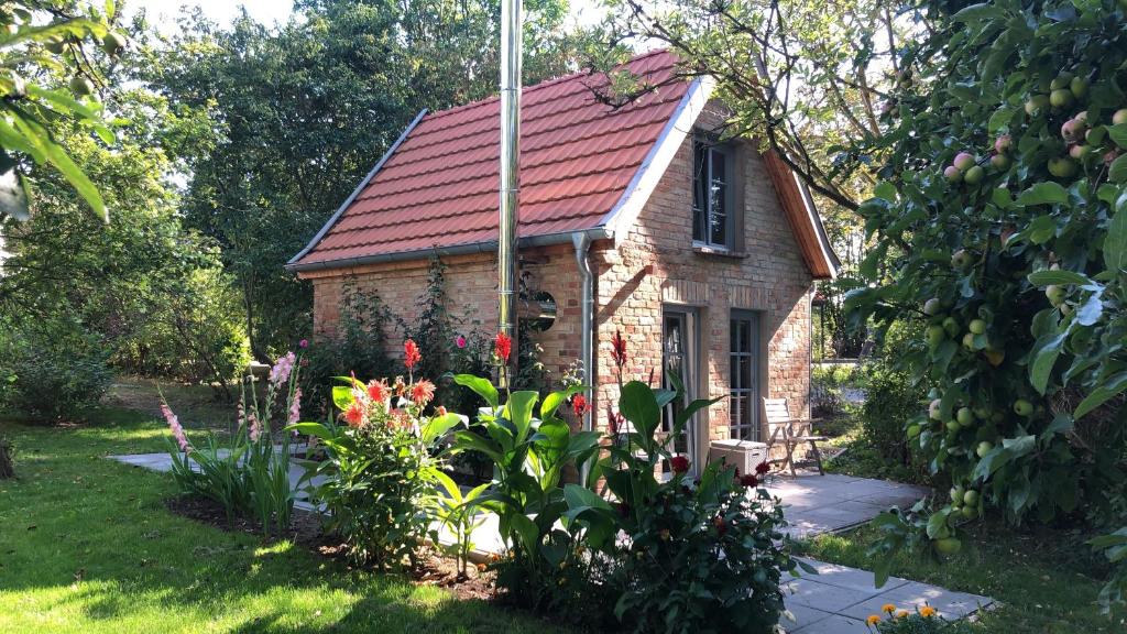 een klein bakstenen huis met een rood dak bij Honeymoon, kleines aber feines Cottage am Strand in Kalkhorst