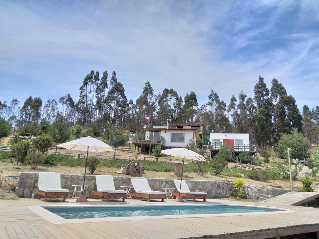 una piscina con sillas y sombrillas y una casa en Cabanas Vista Mar, en San Antonio