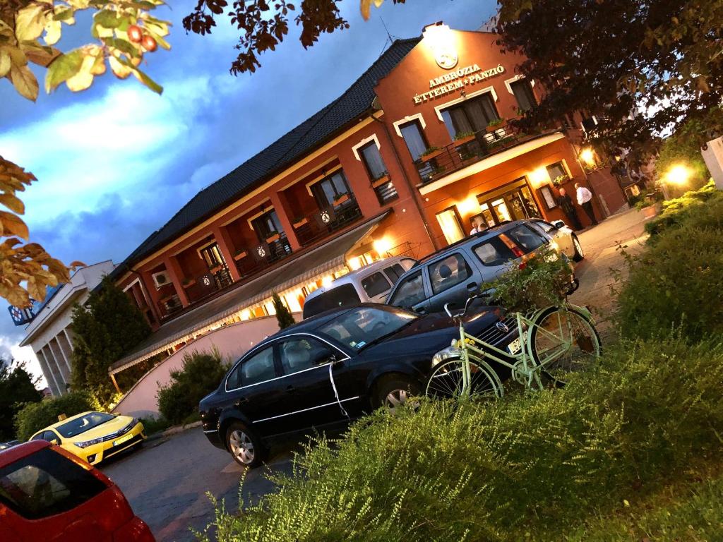 a couple of cars parked in front of a building at Ambrózia Étterem és Panzió in Kazincbarcika