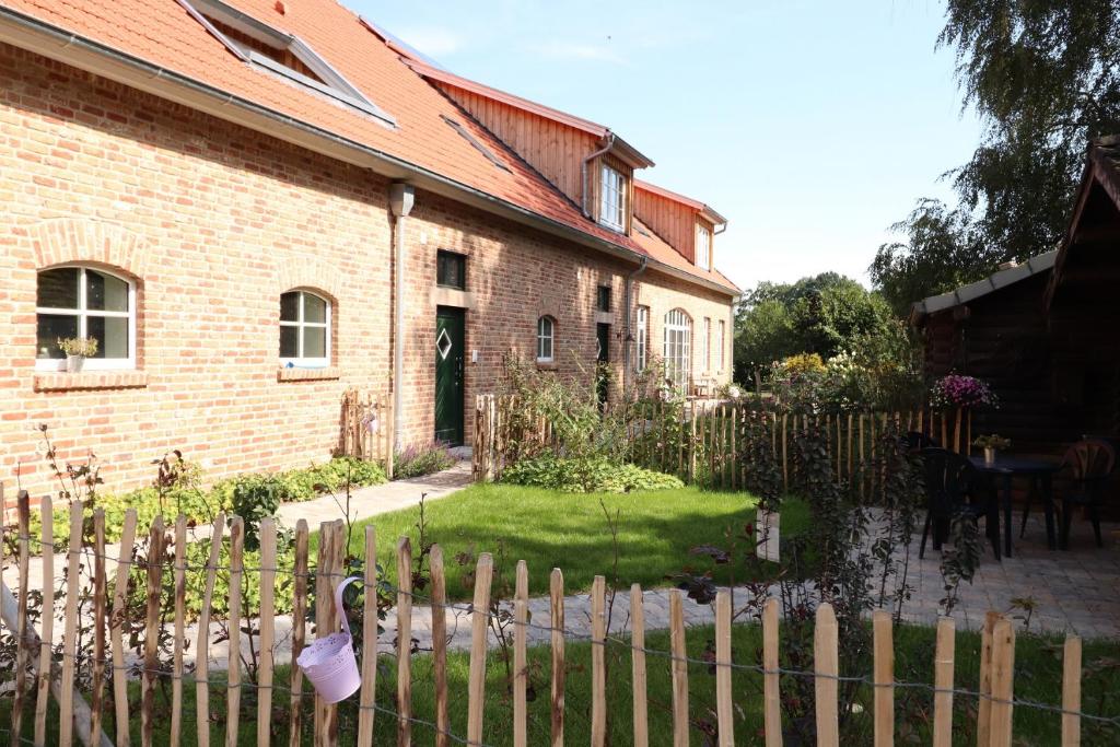 ein Backsteinhaus mit einem Zaun davor in der Unterkunft Ferien- und Reiterhof Klein Stavern in Stavern 