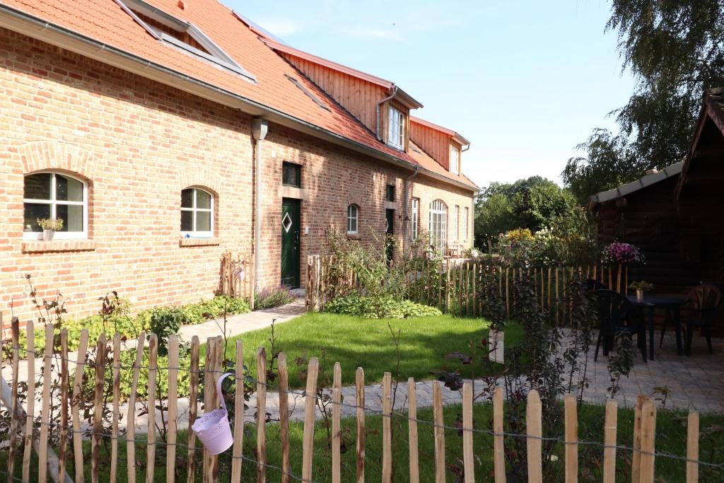 a brick house with a fence in front of it at Ferien- und Reiterhof Klein Stavern in Stavern 