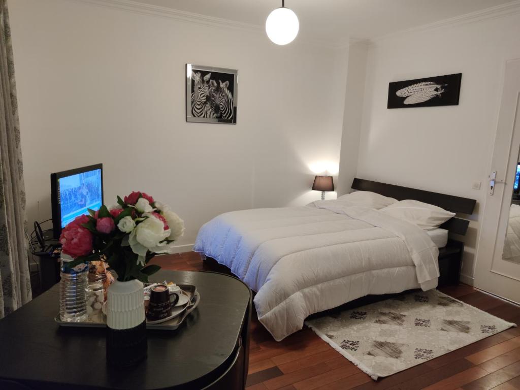 um quarto com uma cama e uma mesa com flores em Appartement tout équipé au calme - RefKL em Montfermeil
