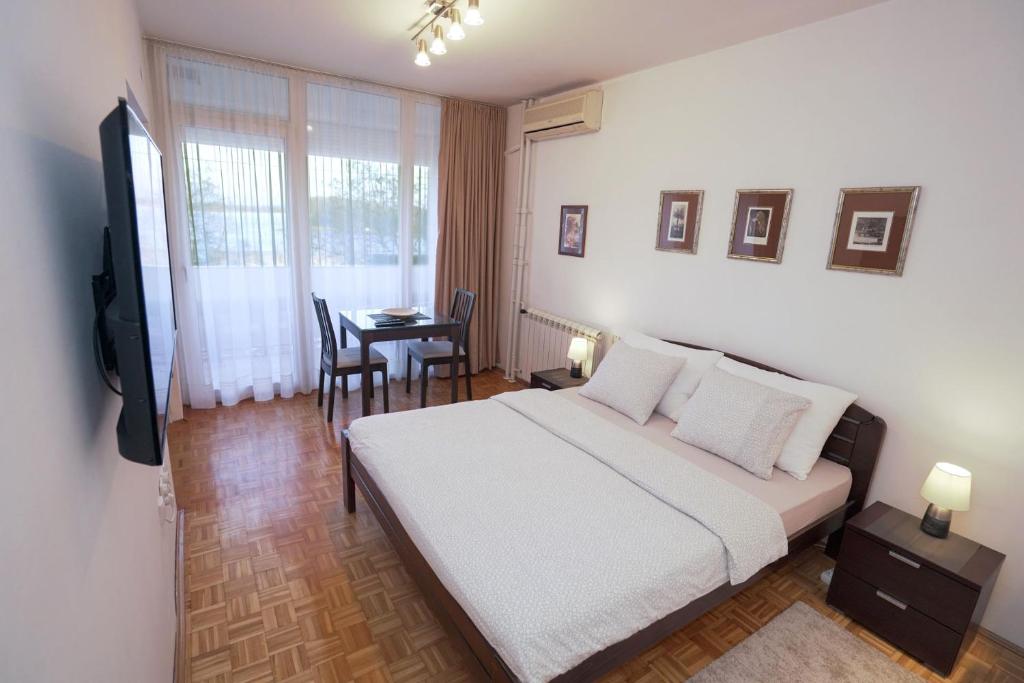 a bedroom with a bed and a table and a television at Apartman Lido in Belgrade