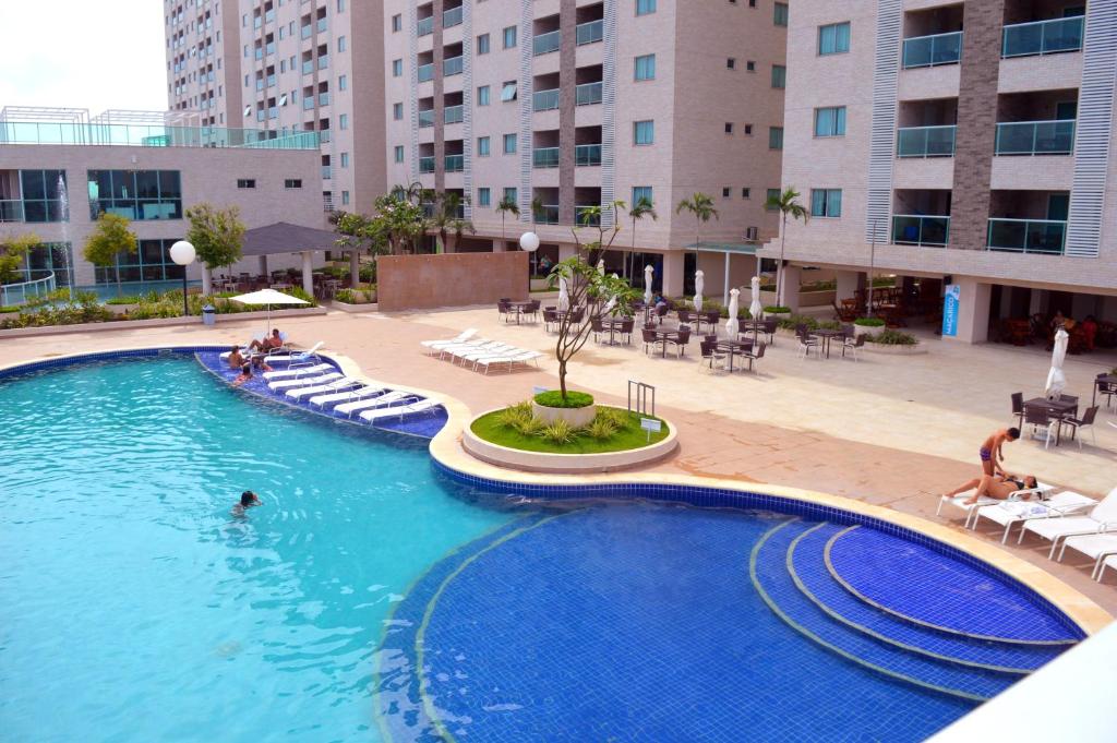 a large swimming pool with chairs and tables and buildings at Salinas Park Resort in Salinópolis