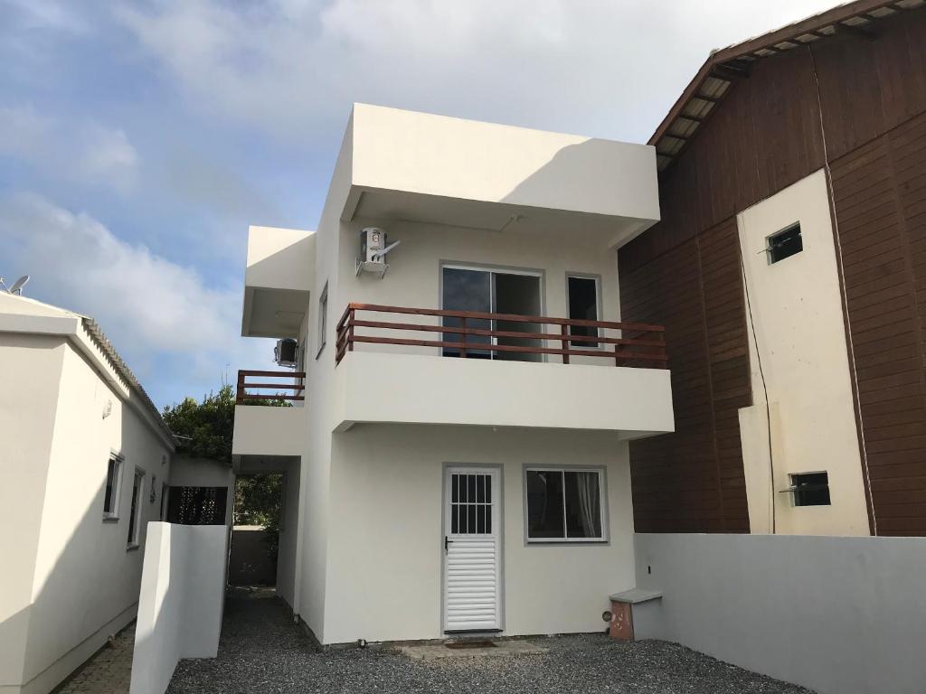 Una casa blanca con un balcón en el lateral. en Casa temporada Mariscal, Bombinhas-SC, en Bombinhas