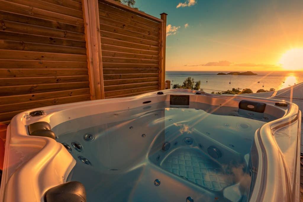 une baignoire jacuzzi avec un coucher de soleil en arrière-plan dans l'établissement Sunset Lodge, à Bouillante