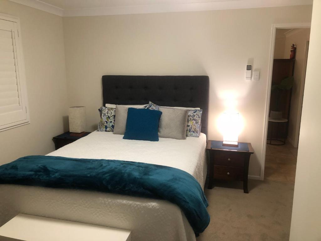 a bedroom with a large bed with blue pillows at Woodford Gardens in Woodford