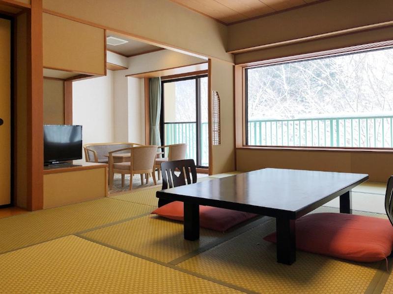 みなかみ町にあるホテル湯の陣のテーブルとテレビのあるリビングルーム