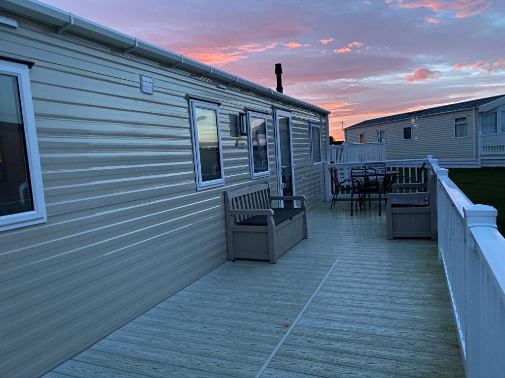 a deck with chairs and tables on the side of a building at Paul’s place silversands in Lossiemouth