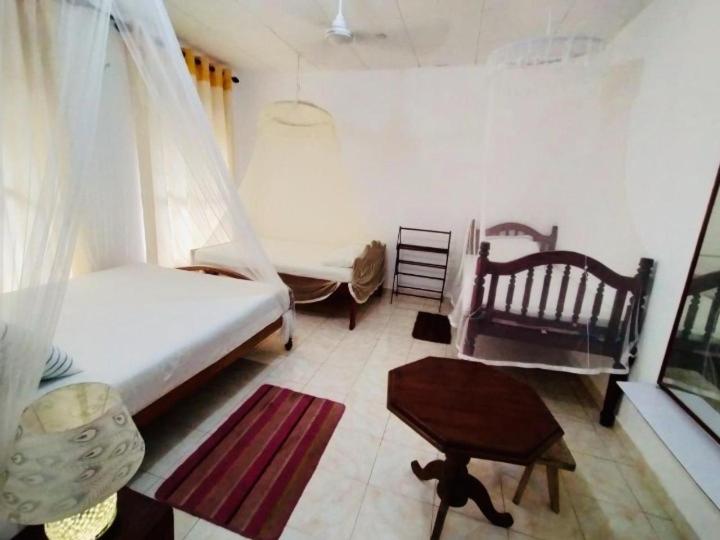 1 dormitorio con 2 camas, mesa y silla en Kadolana Guest House, en Mirissa