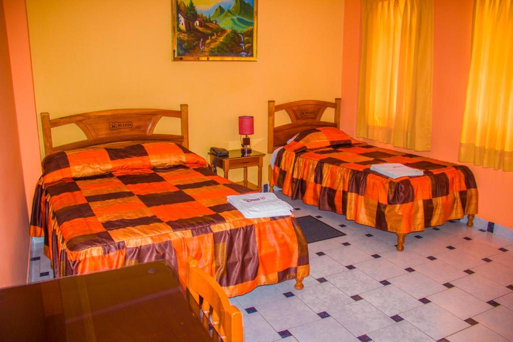 a bedroom with two beds and a table with a tv at Hotel Mi Casa in Ayacucho