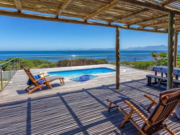 a deck with two chairs and a swimming pool at Whale Sea Cottage in Gansbaai