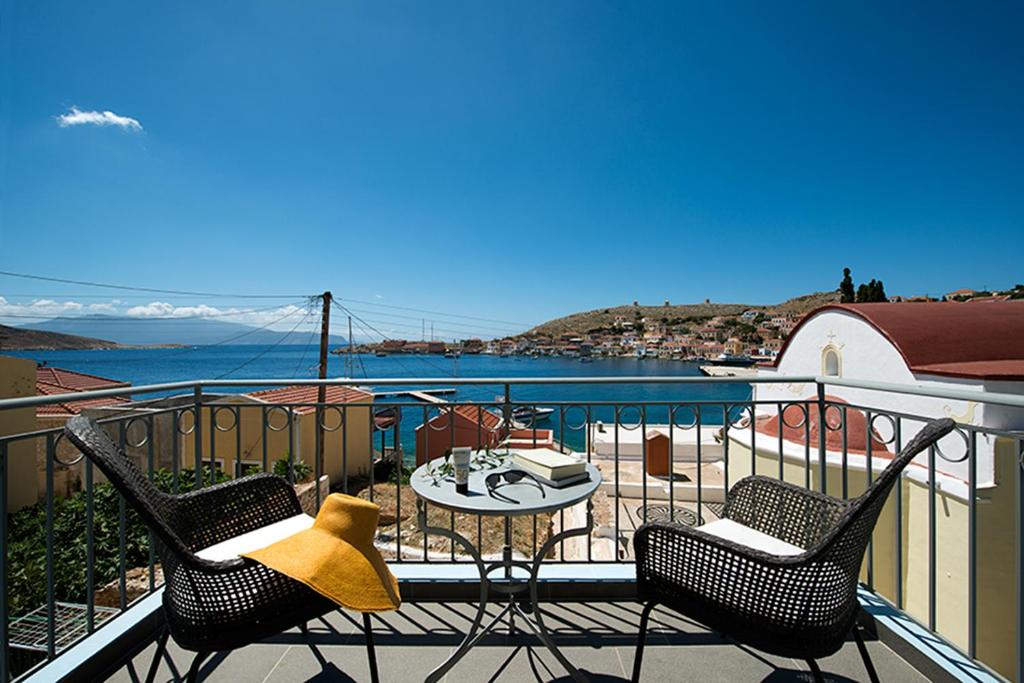 balcón con mesa, sillas y vistas al agua en Villa Kalypso, en Halki