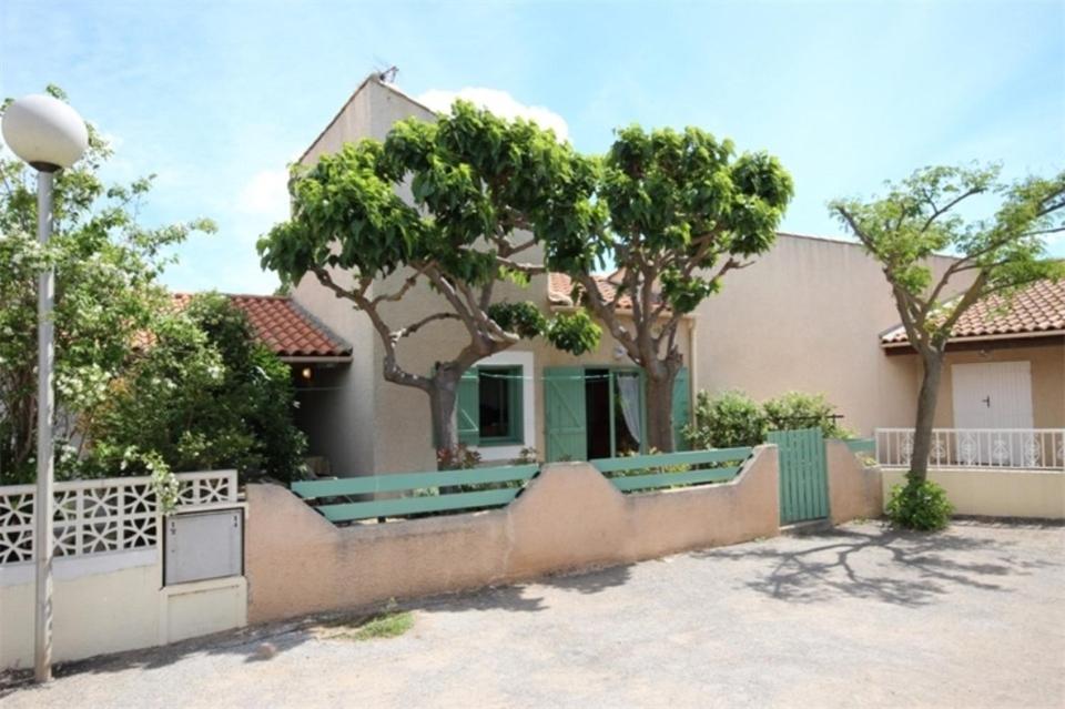 uma casa com uma cerca em frente em 300m de la plage, adorable maison sud 2 chambres 5 couchages terrasse ombragée parking LRHP14 em Portiragnes