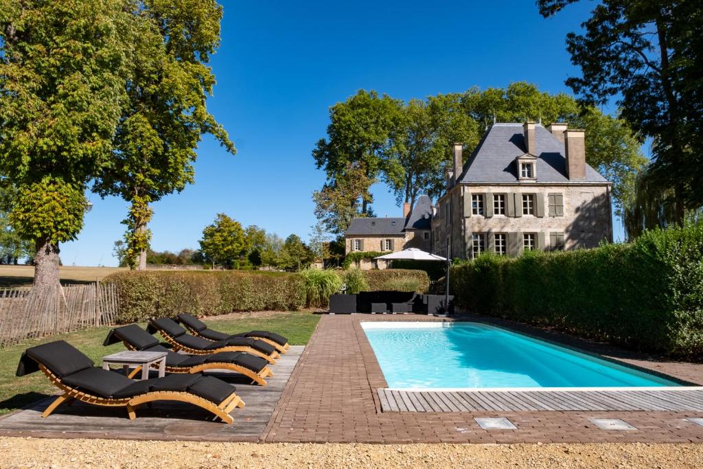 a row of lounge chairs next to a swimming pool at La ferme de Planchevienne in Magny-Cours