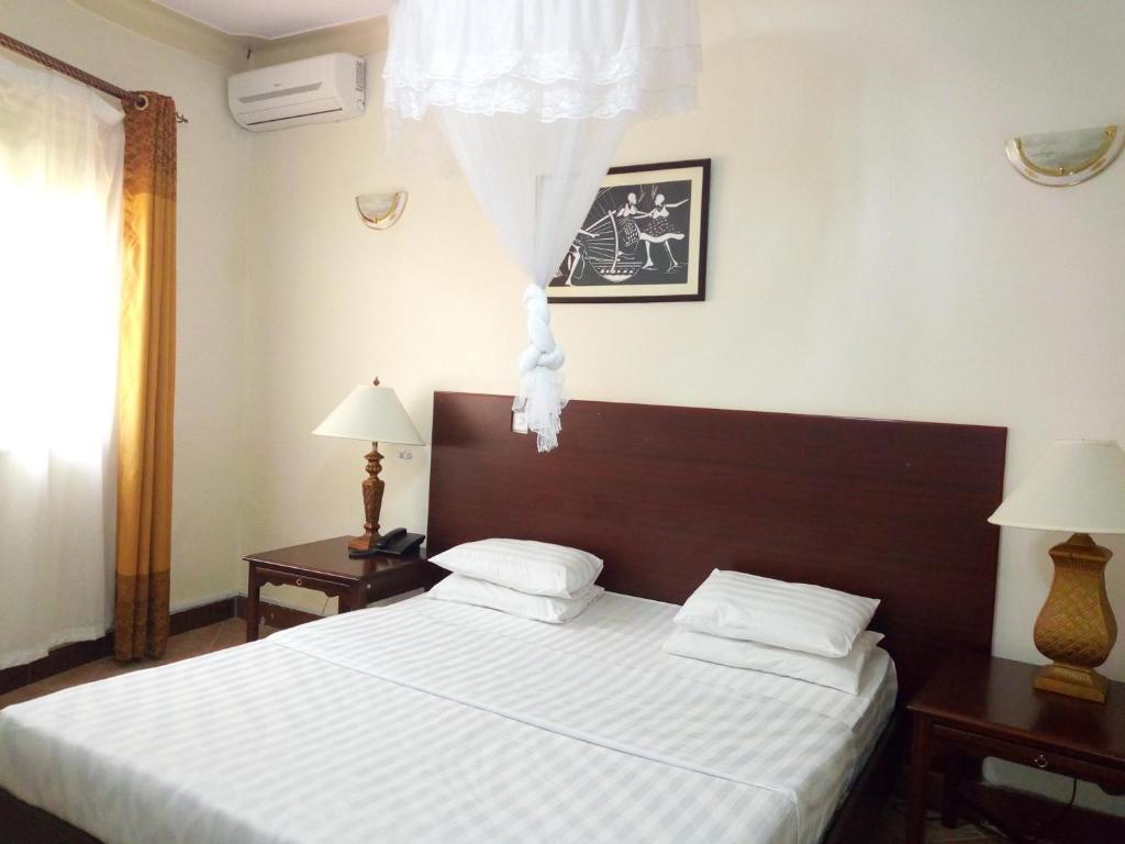 a bedroom with a bed and two lamps and a window at Peniel Beach Hotel in Entebbe