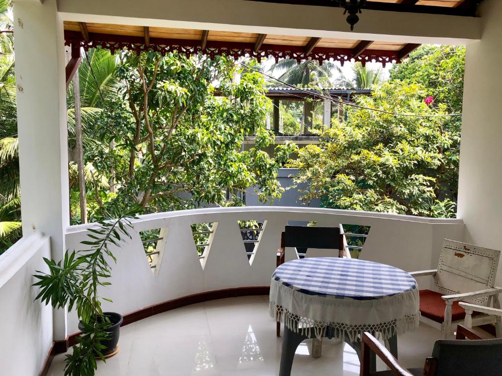 a porch with a table and chairs and trees at Eden Homestay in Hikkaduwa