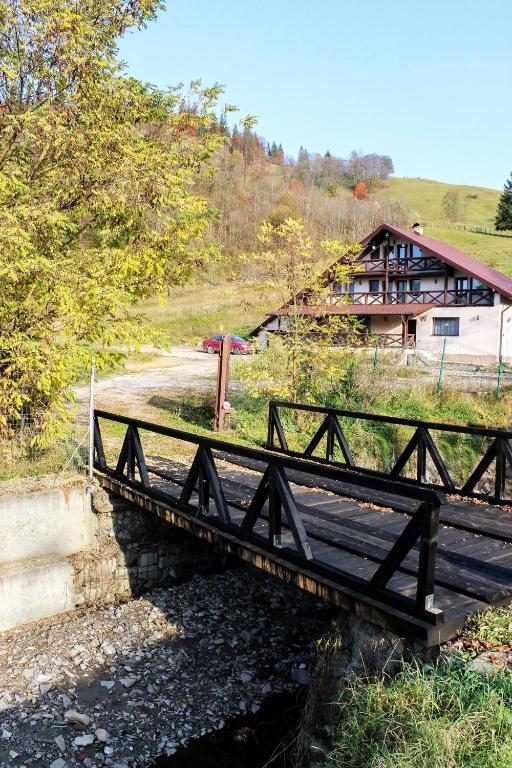 a wooden bridge over a river with a building in the background at Casa Roua Muntilor in Câmpulung Moldovenesc
