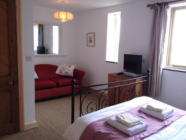 a bedroom with a bed and a red couch at Three Chimneys Farm Accommodation in Goudhurst