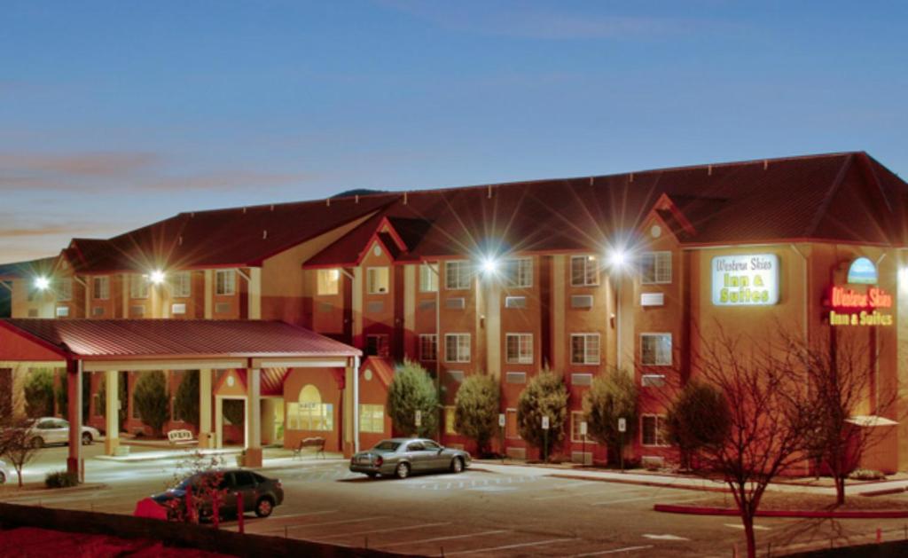 un hotel con coches estacionados en un estacionamiento por la noche en Western Skies Inn & Suites, en Los Lunas