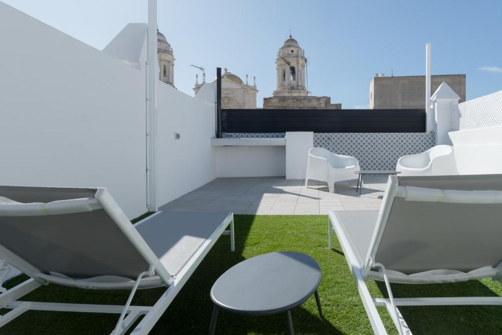 a rooftop patio with chairs and grass at Atico Gades de la Catedral in Cádiz